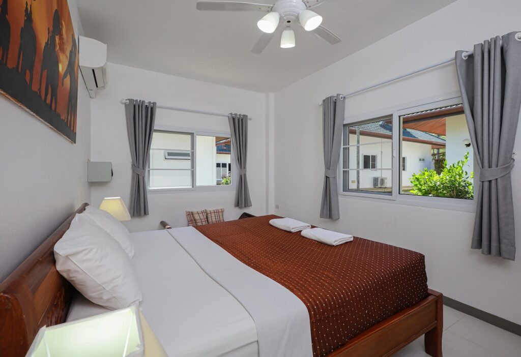 Spacious and bright bedroom in Yanui Breeze apartment, featuring a king-size bed and large windows.