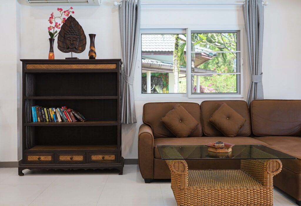 Elegant living room in Yanui Breeze apartment, featuring a comfortable sofa, bookshelf, and tropical decor.