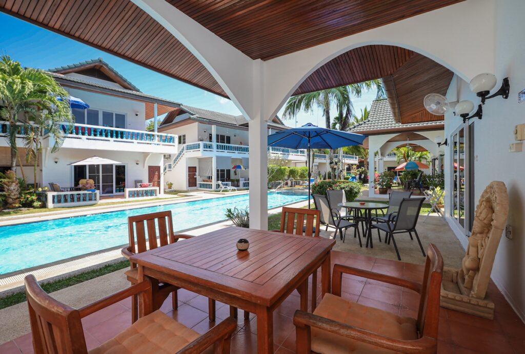 Shaded outdoor terrace at Yanui Breeze in Phuket, overlooking the swimming pool and tropical gardens.