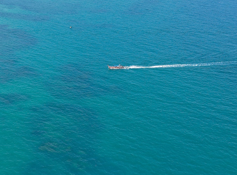 A tour boat sailing near Rawai Beach in Phuket, offering island-hopping trips close to Yanui Breeze.