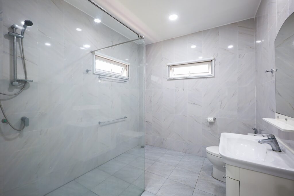 Modern and spacious bathroom in Yanui Breeze apartment, featuring a walk-in glass shower and elegant tiling.