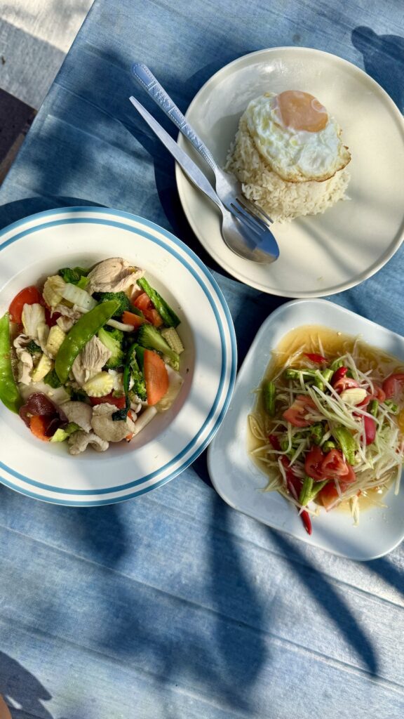 A combination of Thai vegetable stir-fry, egg fried rice, and fresh papaya salad.